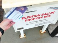 A voter drops ballots into a drop box in Centennial.