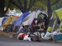 Belongings pile up outside tents during a sweep of a homeless encampment around the intersection of 14th Avenue and Logan Street near the State Capitol early Tuesday, Oct. 6, 2020, in downtown Denver. (AP Photo/David Zalubowski)