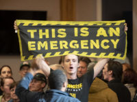 A climate change protester holds a banner reading "This Is An Emergency," during a town hall event with former Vice President Joe Biden, 2020 Democratic presidential candidate, not pictured, in Manchester, New Hampshire, U.S., on Wednesday, Oct. 9, 2019. Biden said for the first time Wednesday that President Donald Trump should be impeached. Photographer: Kate Flock/Bloomberg