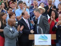 Colorado Gov. John Hickenlooper, right, shakes then Gubernatorial candidate Jared Polis's hand at a rally last summer.